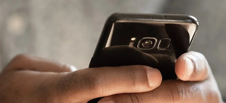 A close-up of a person's hands holding a smartphone, focusing on the device's sleek design and camera.