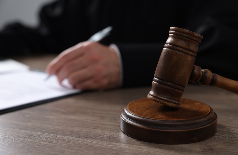 Judge with gavel writing in papers at wooden table