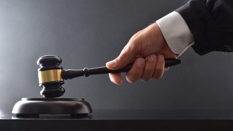 Hand striking on wooden base with judge's mallet on black table