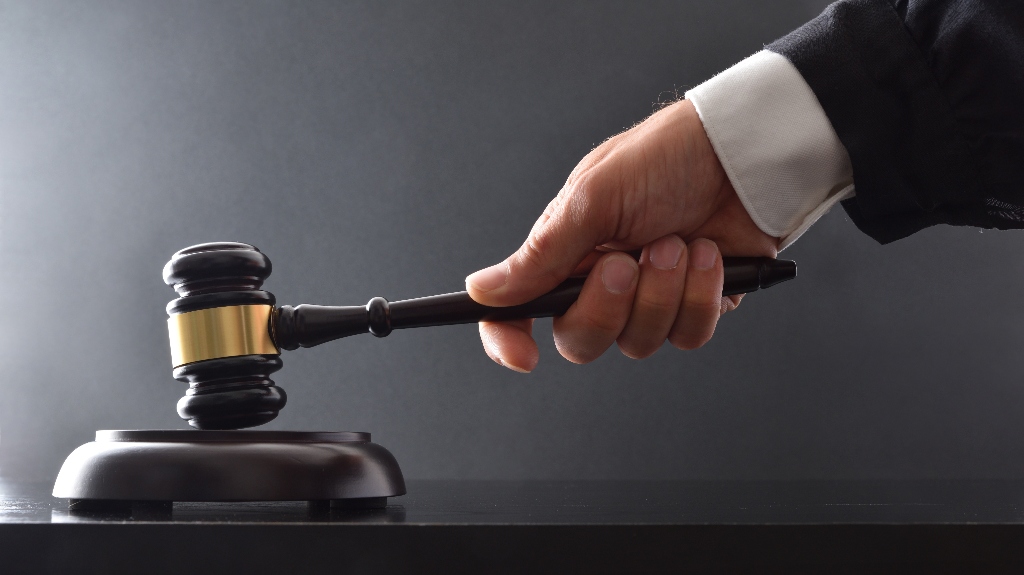 Hand striking on wooden base with judge's mallet on black table