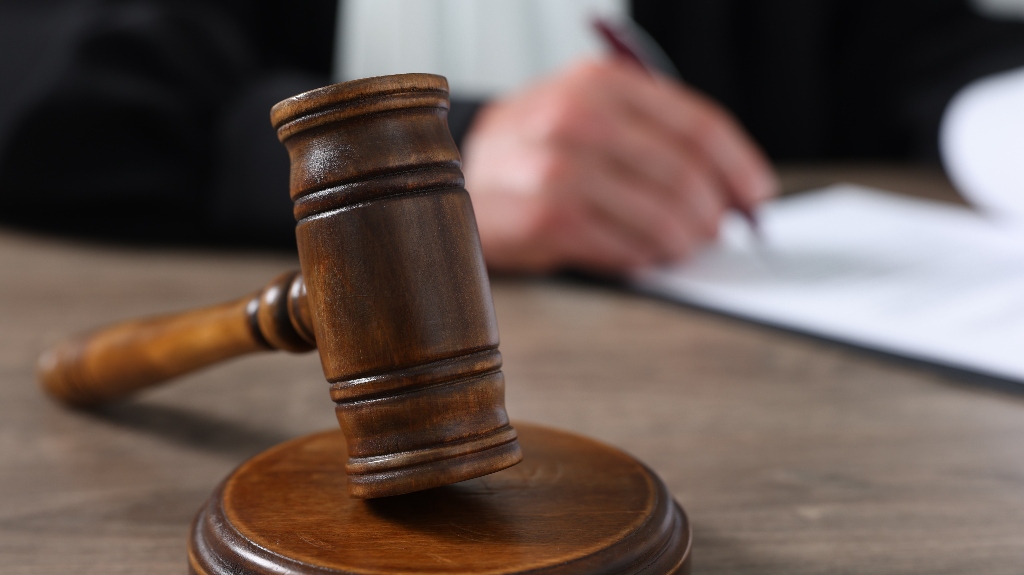 Judge with gavel writing in papers at wooden table