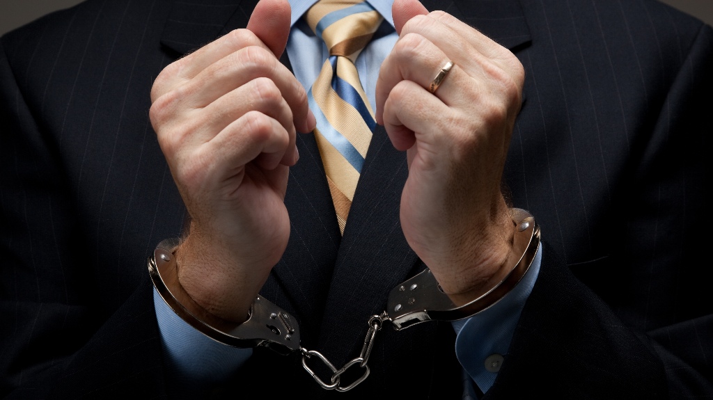 A man in a blue business suit holding hands in handcuffs