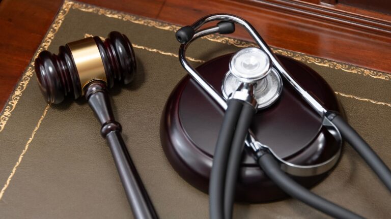 judge's gavel and a black stethoscope on top of a legal book