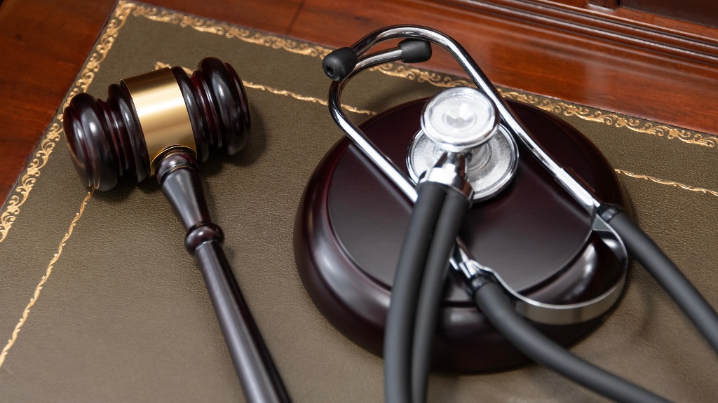 judge's gavel and a black stethoscope on top of a legal book