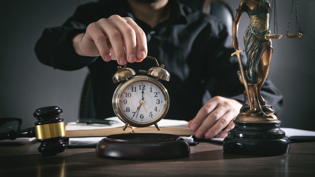 man holding a clock with gavel on desk
